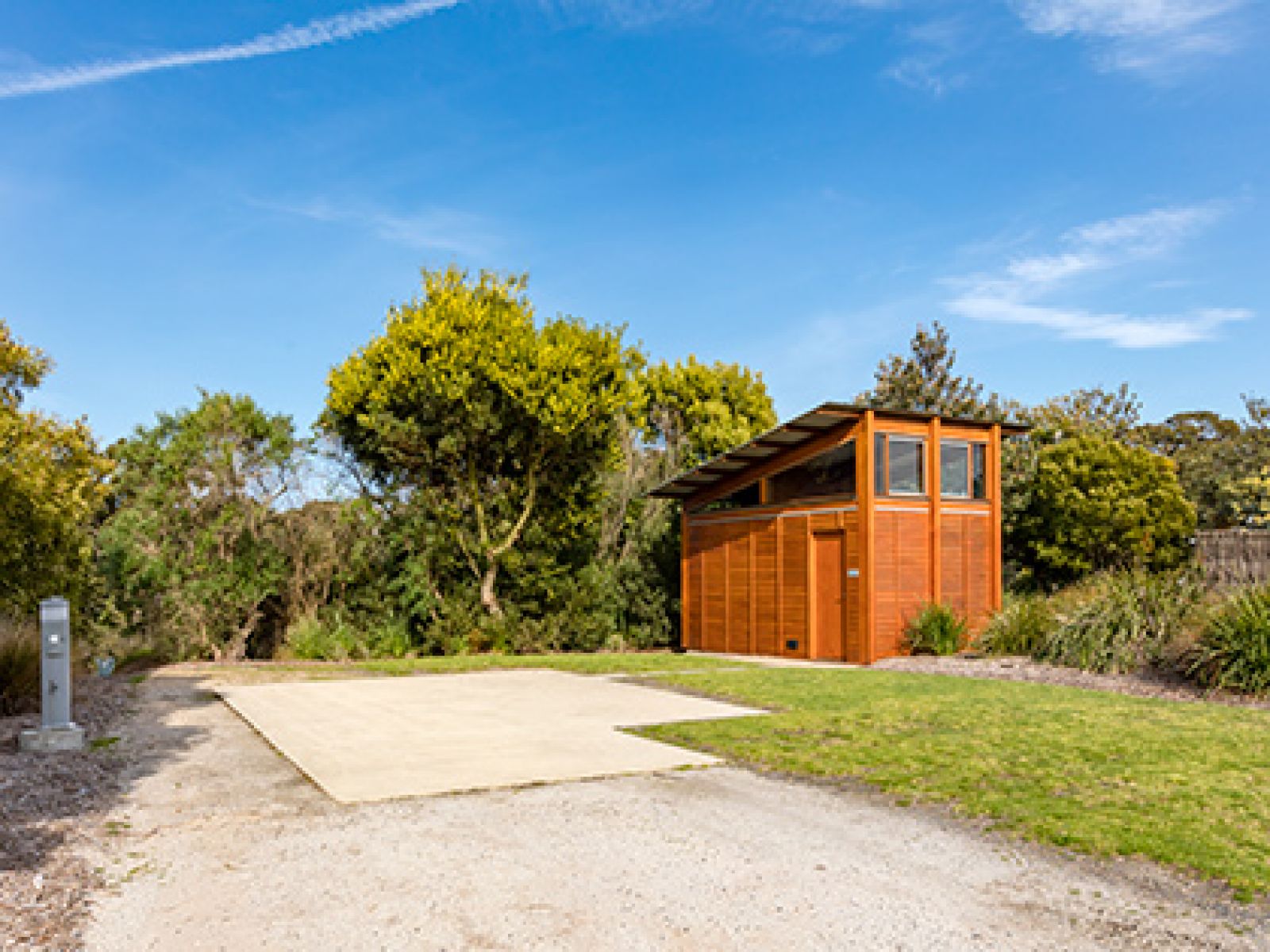 Ensuite caravan site at RACV Inverloch Resort, featuring a space to park a caravan and a wooden toilet block.
