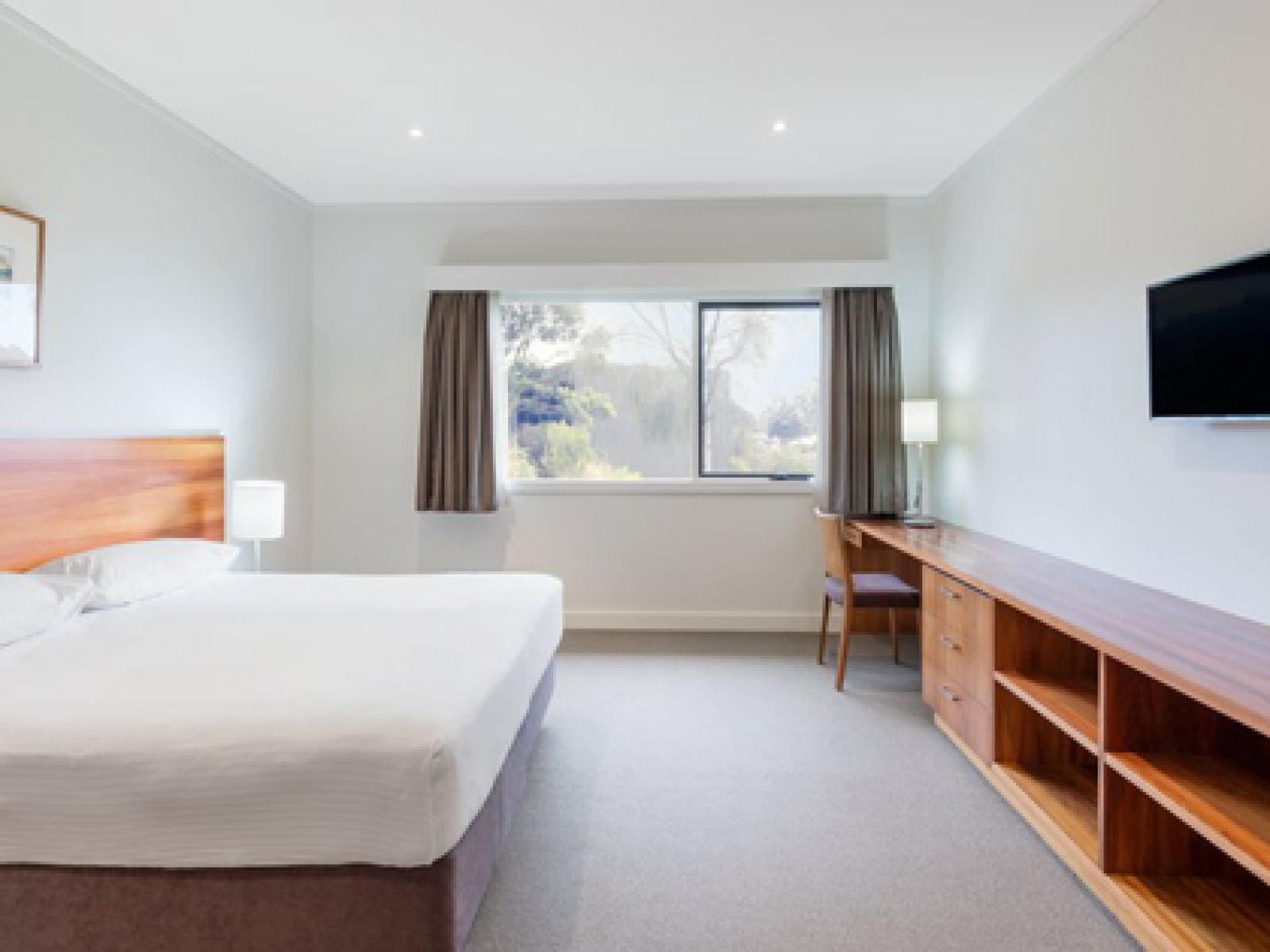 Premium villa at RACV Inverloch Resort, featuring a large bed, wooden cabinets and desk.