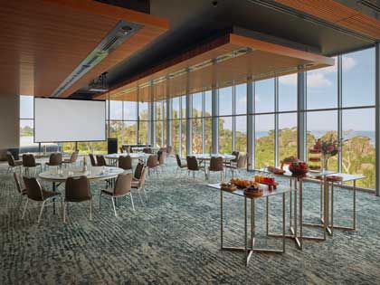 Cape Paterson room at RACV Inverloch Resort, set up cabaret style, with catering on a table and a screen coming down from the ceiling. and food station.