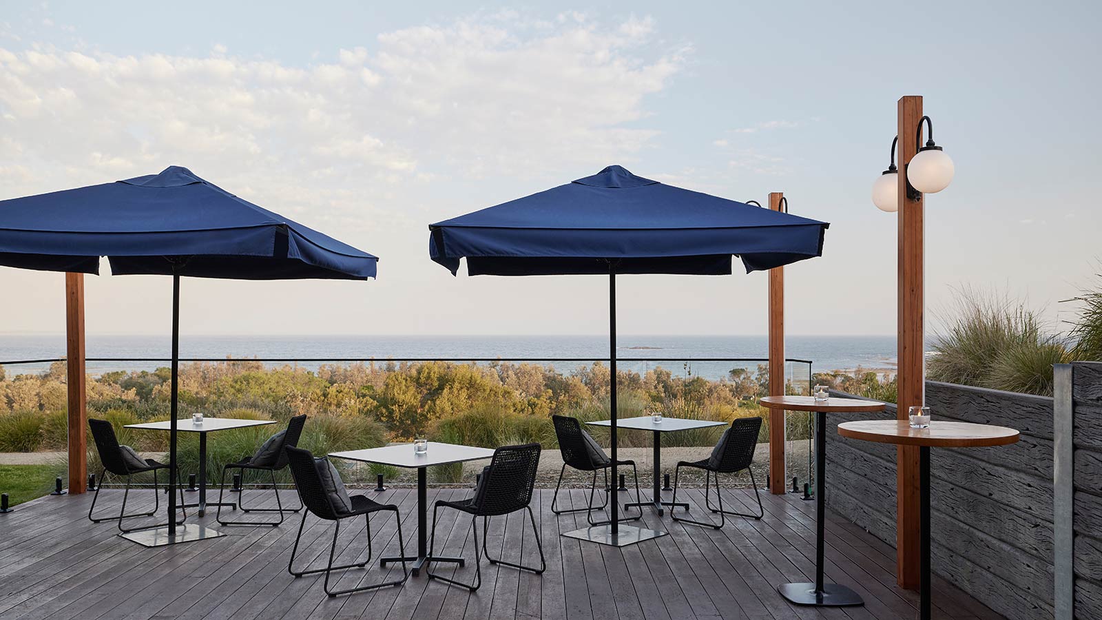 Outdoor dining deck area at RACV Inverloch Resort, featuring tables and chairs facing the beach.