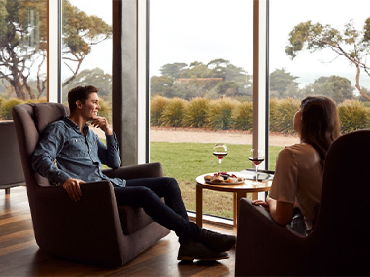 Couple seated with wine and snacks by a window at RACV Inverloch Resort.