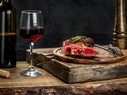 A steak and win dinner prepared on a wooden chopping board