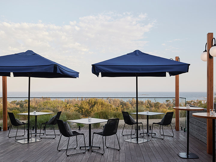Outdoor dining deck area at RACV Inverloch Resort, featuring tables and chairs facing the beach.