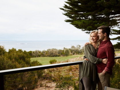 A couple having a cuddle on a balcony overlooking the ocean. 
