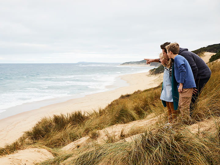 Parent and two kids standing together on the beach near RACV Inverloch Resort.