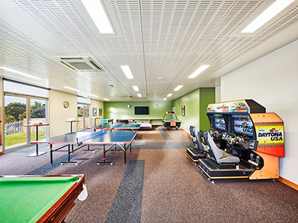 Games room at RACV Inverloch Resort, featuring arcade machines and pool, table tennis and air hockey tables.
