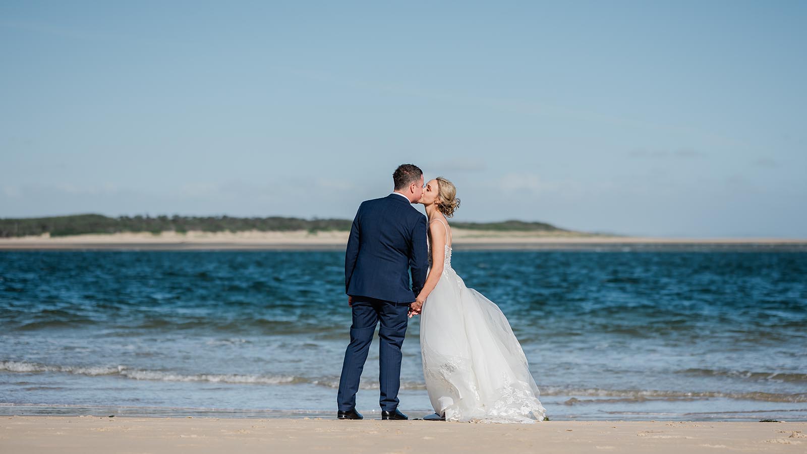 Bride and groom kissing on beach near RACV Torquay resort.