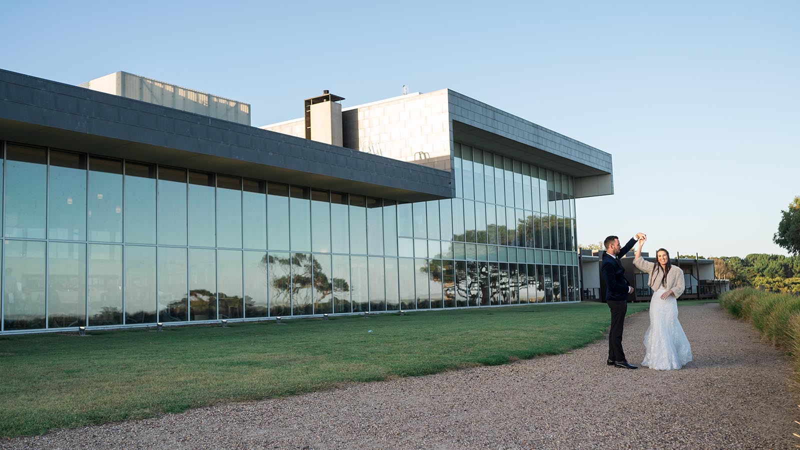 Bride and groom posing in front of RACV's Inverloch resort.