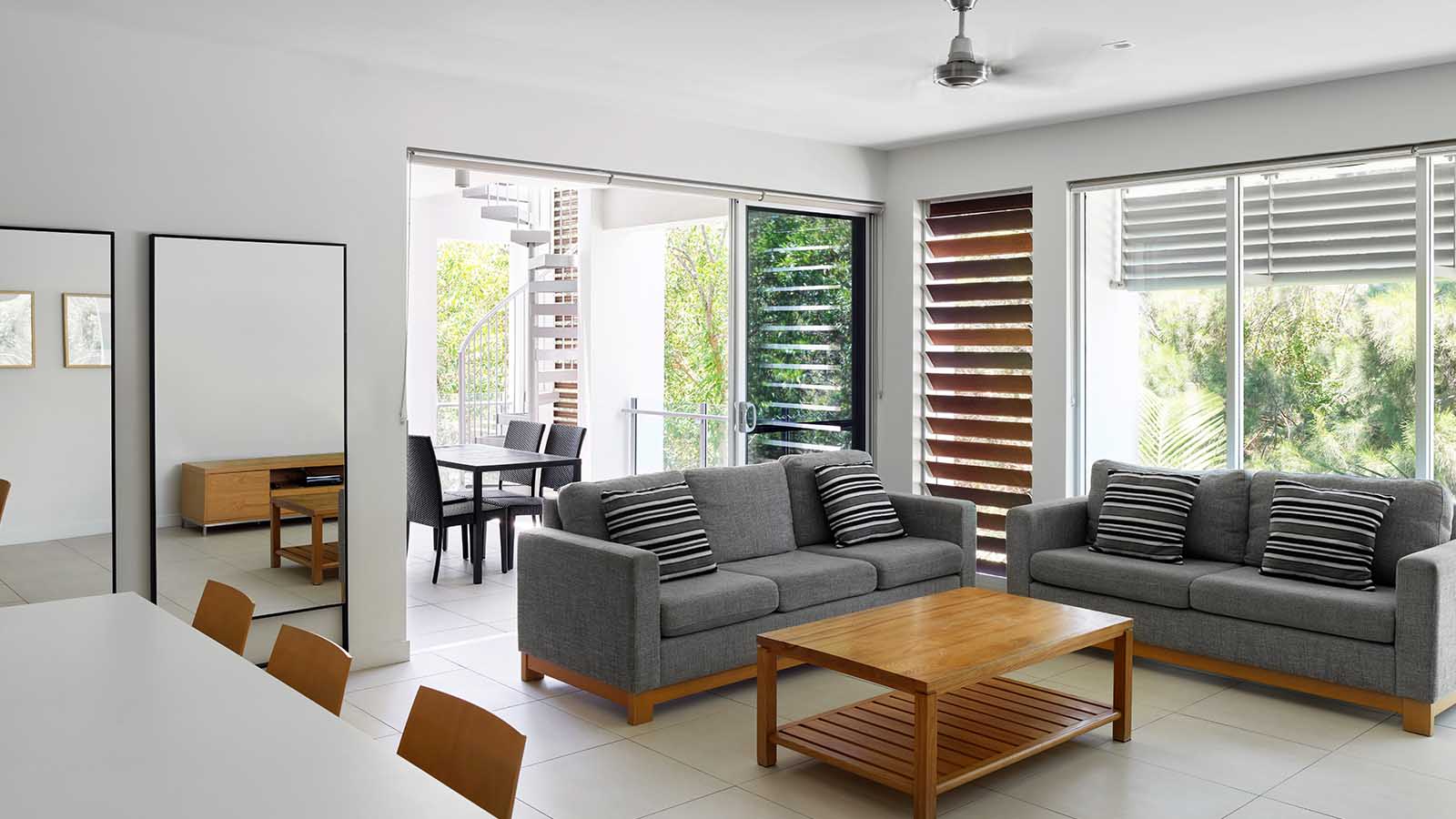 Sanctuary apartment living area at Noosa Resort, with dining area, living area with couches and an outdoor balcony. 