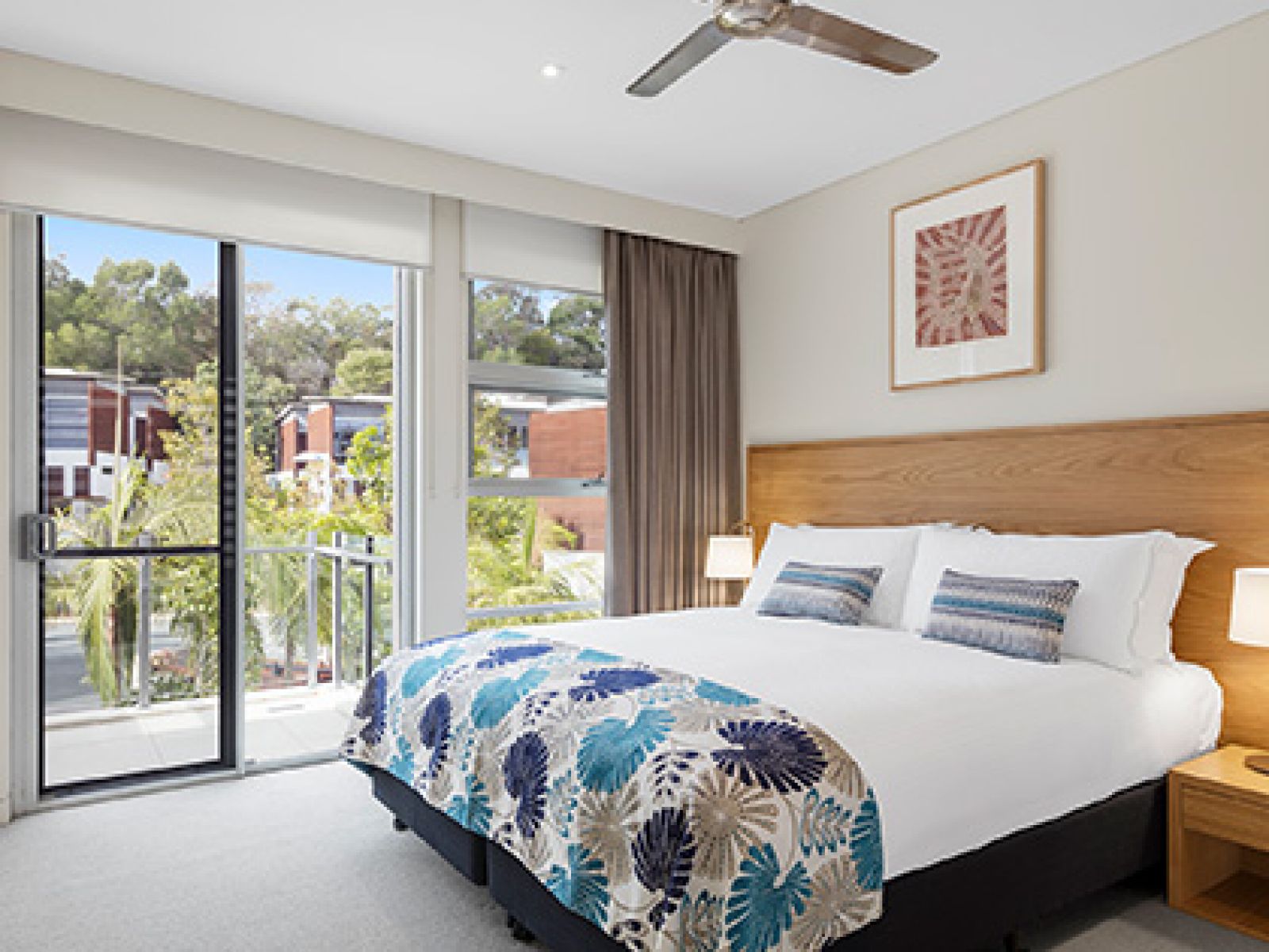 Noosa Resorts three bedroom enclave luxury villa bedroom, featuring a king bed and balcony overlooking palm trees and resort. 