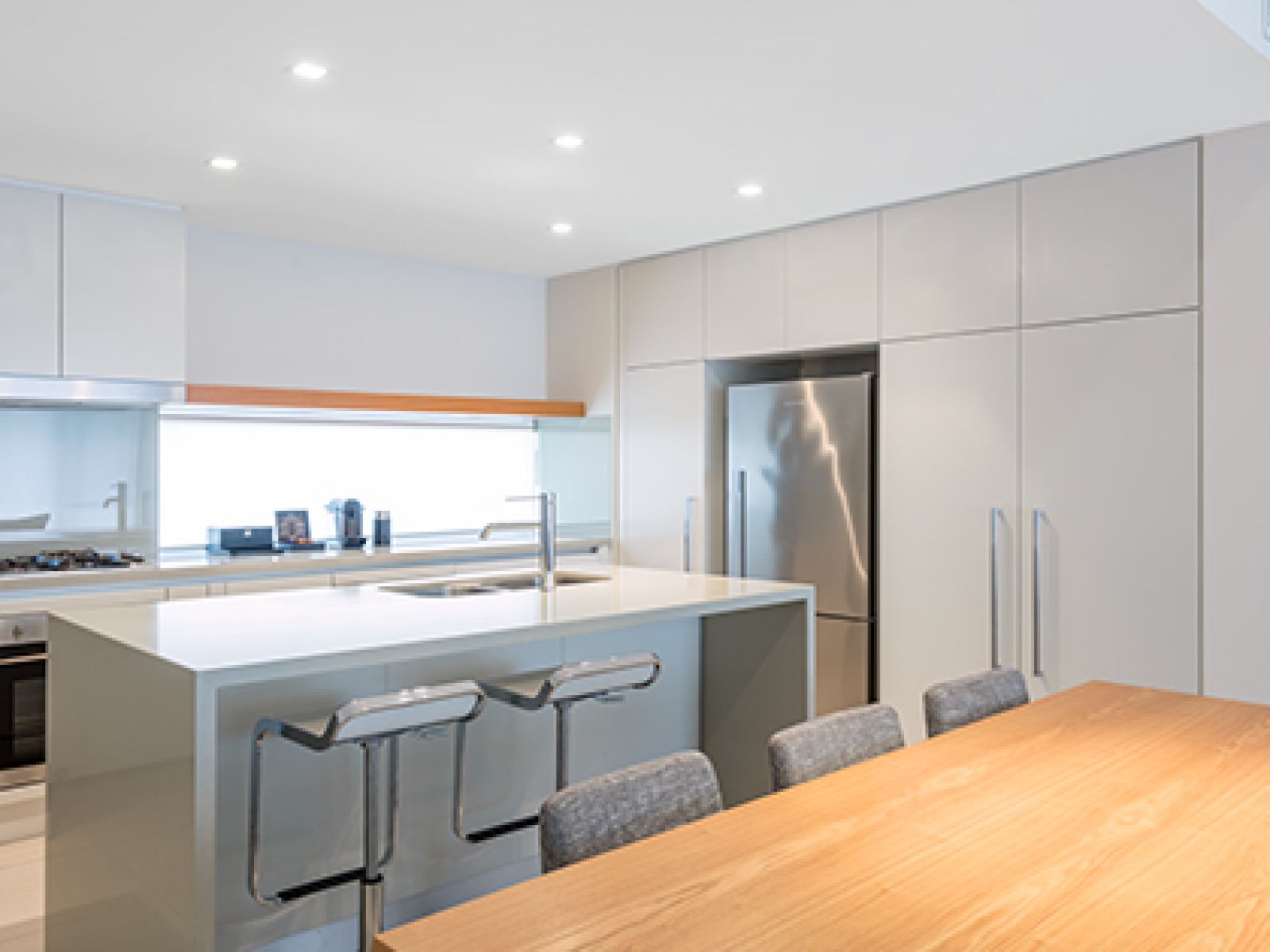 Noosa Resorts two bedroom resort kitchen area, with stainless steel fridge, gas stove, spacious twin sink, Nespresso coffee machine complete with spacious bench space and large dining table. 