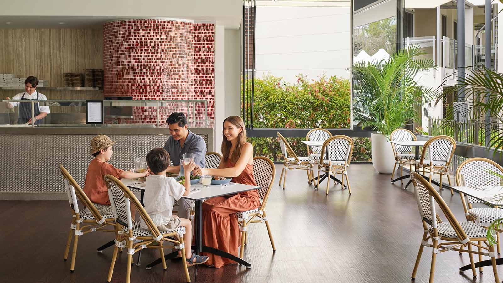 Parents and two children sitting and eating together at Dazza's Bar at RACV Noosa Resort.