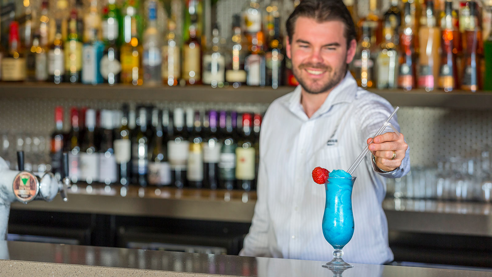 Bartender at Dazza's Bar at RACV Noosa Resort preparing a drink.