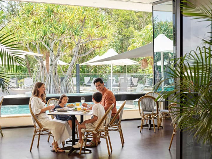 Family dining at RACV's Noosa resort, with views of the pool outside.