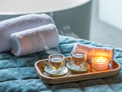 Teacups and a lit candle on a wooden tray in a massage room at RACV Noosa Resort's One Spa.