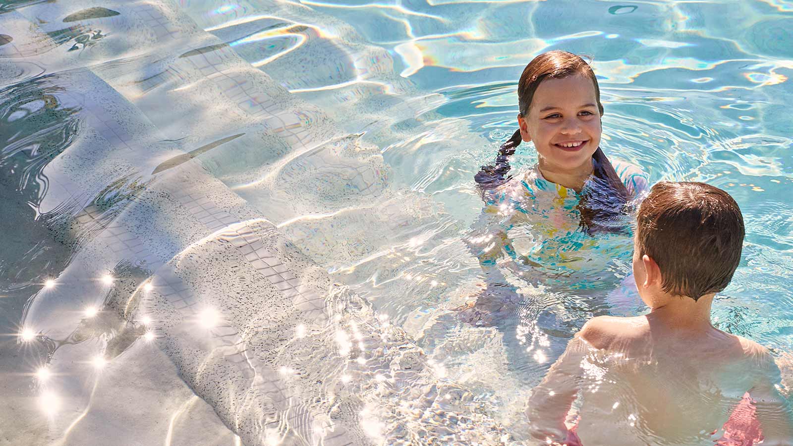 Two children swimming in outdoor pool at RACV Noosa Resort.