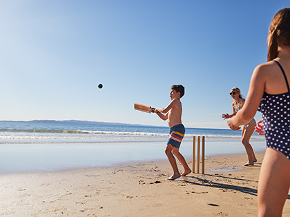 Mother and two kids playing cricket on the beach at RACV Noosa Resort.
