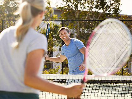 Couple playing tennis and smiling at the Noosa Resort.