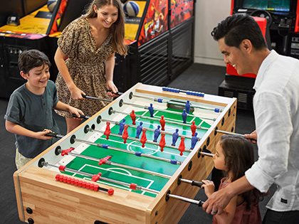 Family playing foosball together in the games room at RACV Noosa Resort.