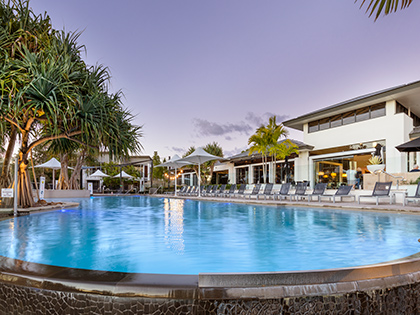 Outdoor pool at RACV Noosa Resort, with a row of pool chairs beside it.