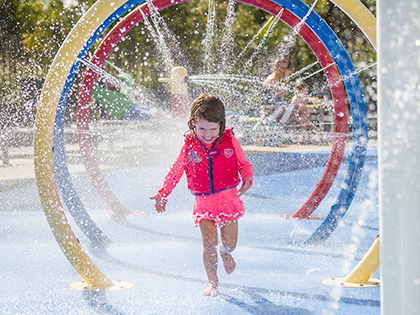 Child running through water jets at RACV Noosa Resort's outdoor water park.