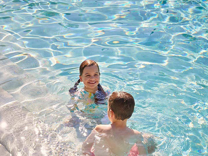 Two children swimming in outdoor pool at RACV Noosa Resort.