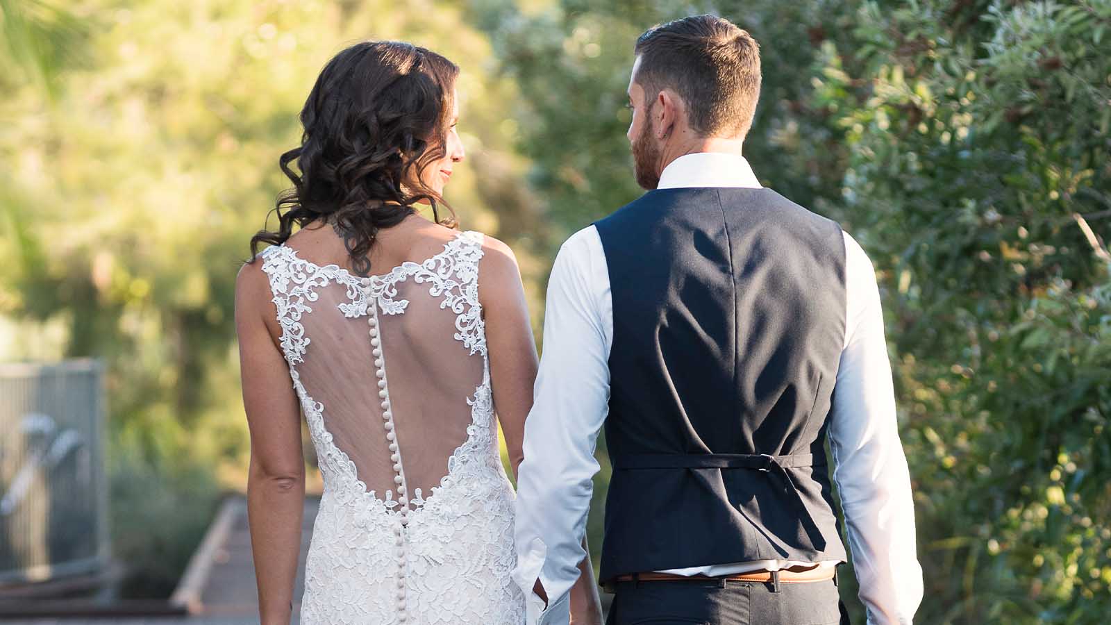 Bride and groom holding hands with their backs to the camera at the Noosa Resort.