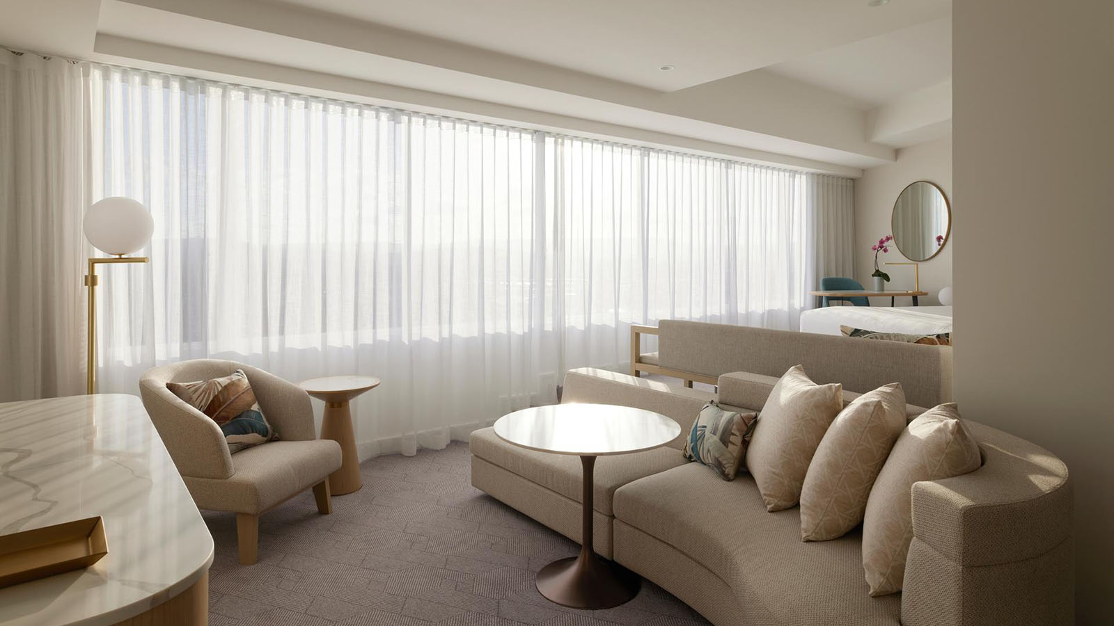Executive Spa Suite at RACV Royal Pines, featuring lounge area with couches, and bedroom area with king bed and desk.