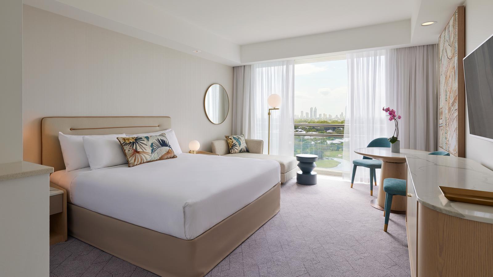 Superior king room at RACV Royal Pines, featuring a king bed, couch and desk.