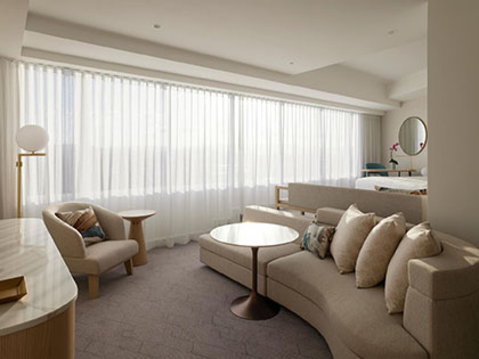 Executive Spa Suite at RACV Royal Pines, featuring lounge area with couches, and bedroom area with king bed and desk.