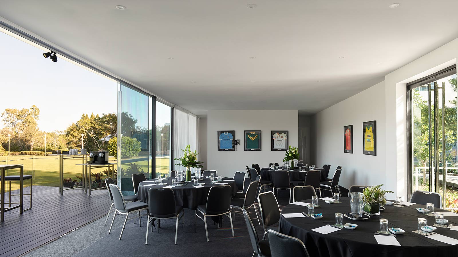 Three tables set up banquet style at RACV Royal Pines Resort, with framed sports jerseys on the wall.