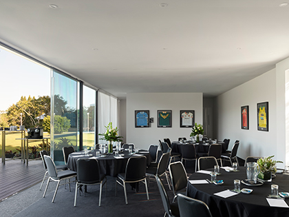 Three tables set up banquet style at RACV Royal Pines Resort, with framed sports jerseys on the wall.