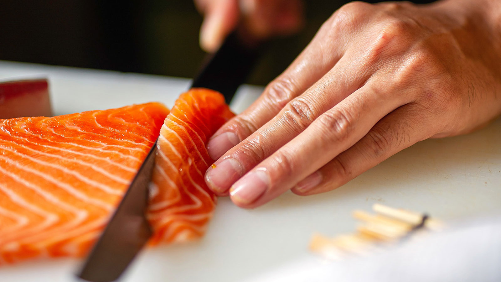 Close up of a chef slicing a piece of salmon