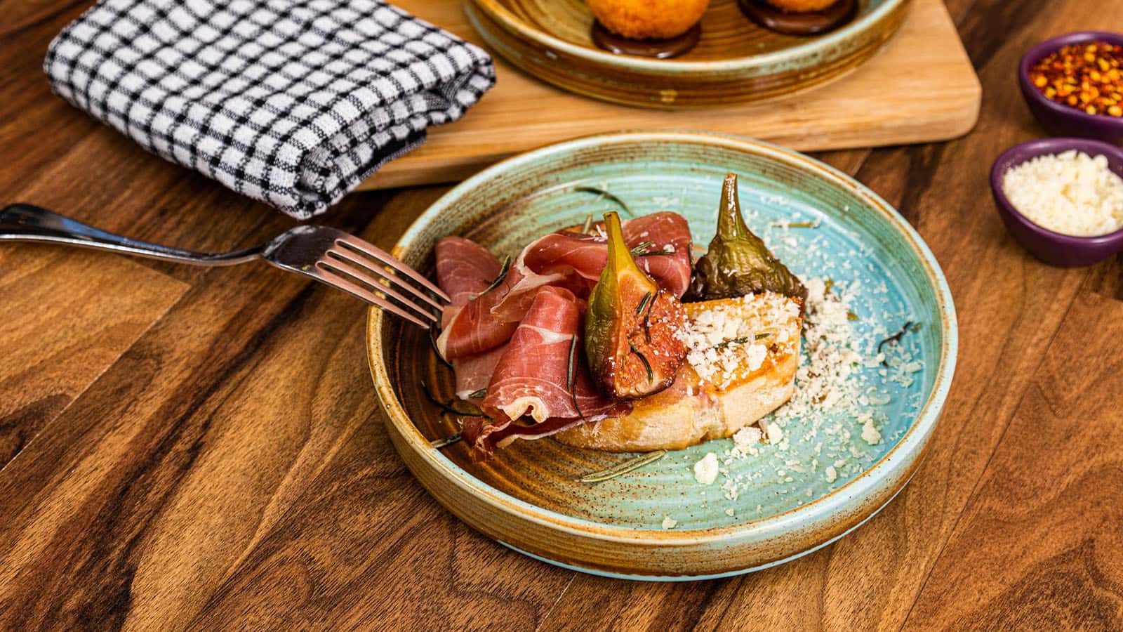 RACV Royal Pines Trattoria Amici's plated dish of fig, prosciutto and cheese on toasted bread.