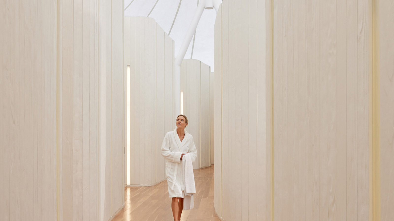 Person in a bathrobe and walking down a hallway at RACV Royal Pines Resort's One Spa.