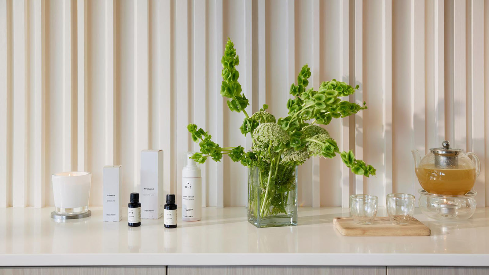 Table featuring products used at RACV Royal Pines Resort One Spa, flowers in a vase, a teapot and two cups.
