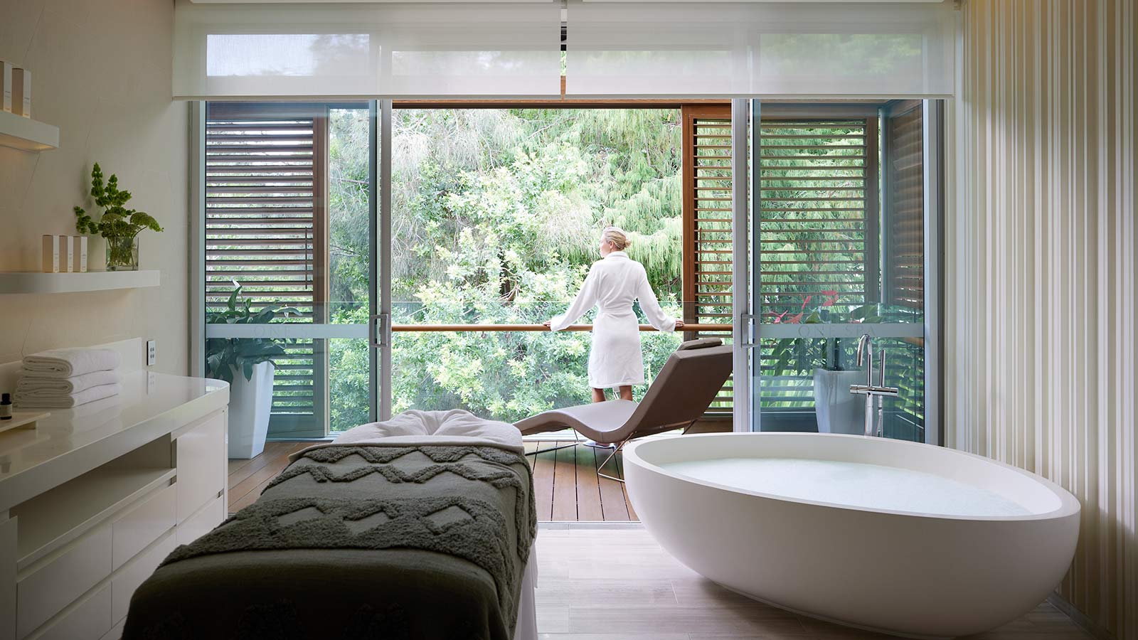Person in bathrobe looking out balcony in a treatment room at RACV Royal Pines One Spa.