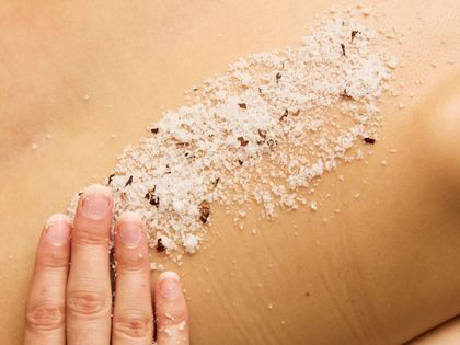 A hand scrubbing a salt mixture into a back. 