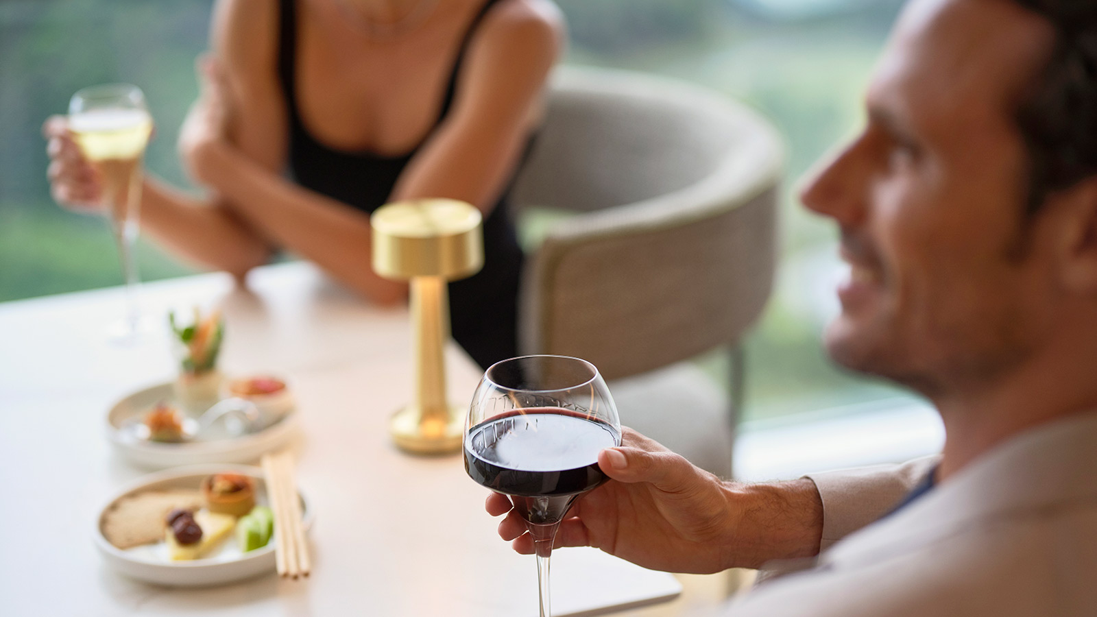 People sitting drinking wine in the Executive Lounge at RACV Royal Pines Resort, with small plates of food in front of them.