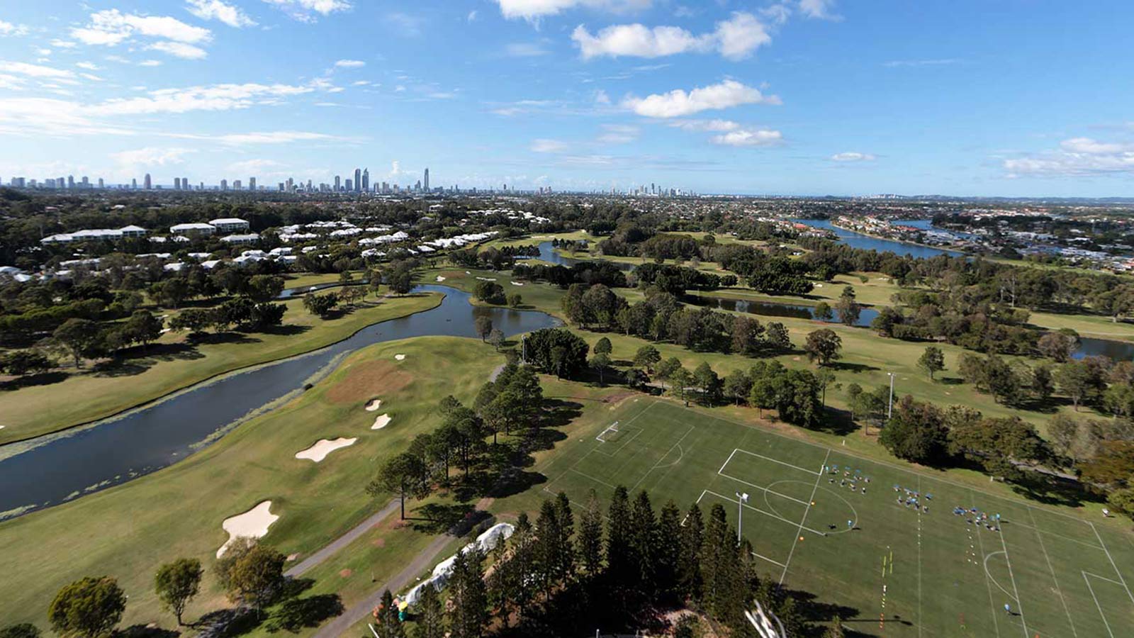 Green football field at RACV Royal Pines Resort, surrounded by trees and a lake.