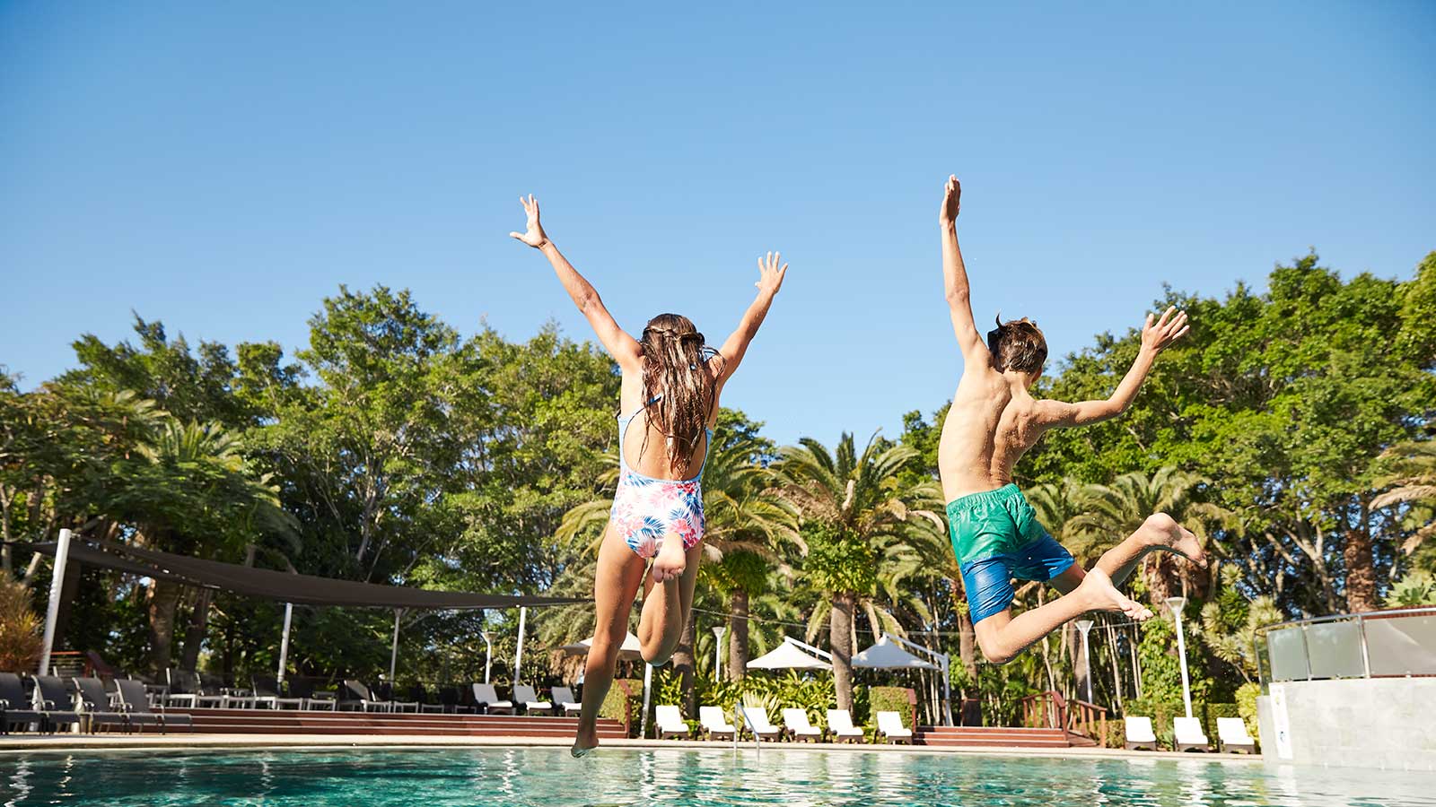 Two children jumping into the RACV Royal Pines outdoor pool.