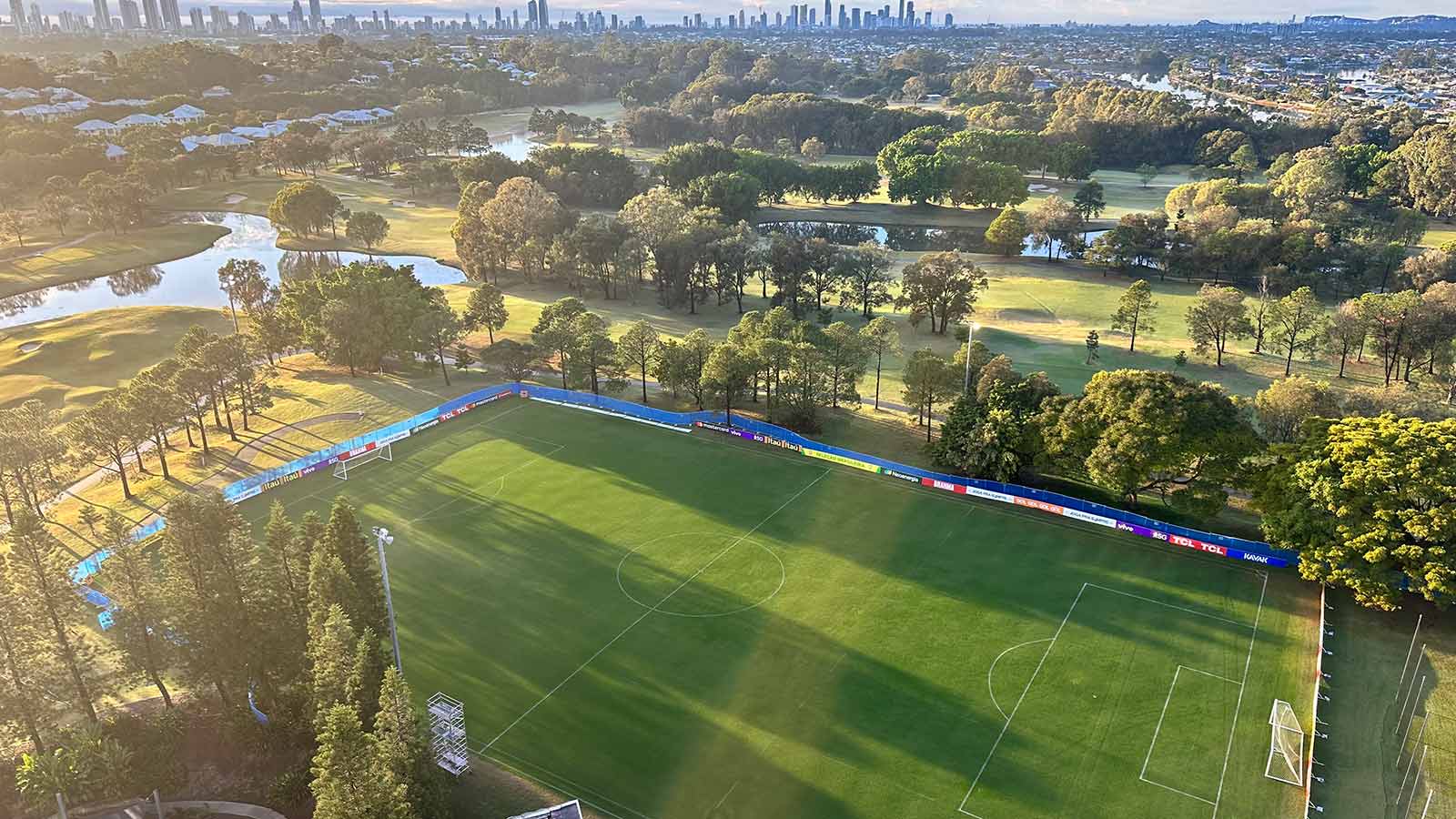 Green sports field at RACV Royal Pines Resort, surrounded by trees and a lake.