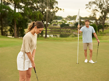 Couple playing golf at Royal Pines near the pond.
