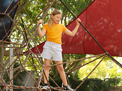 Child standing on the spider web climber at the kids playground at RACV Royal Pines.