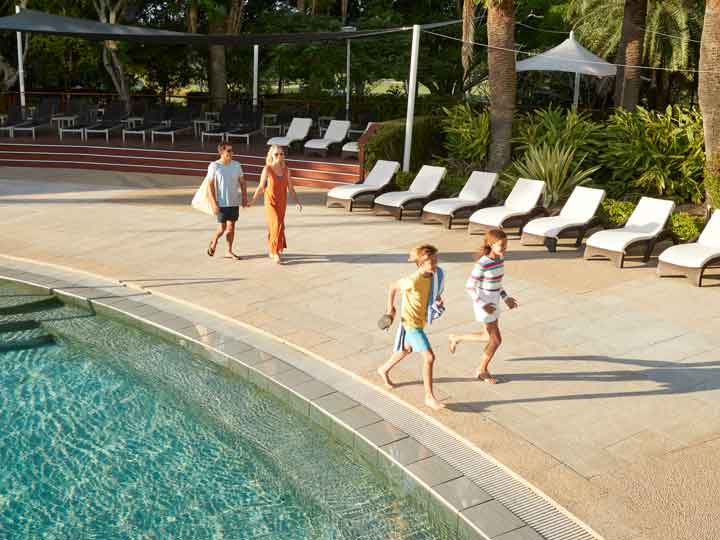 A family walking poolside at RACV Royal pines on a sunny day. 