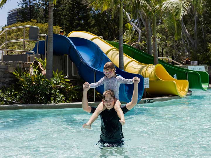 Two kids having fun in the pool near the waterslides at Royal Pines. 