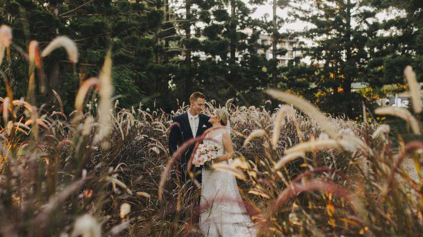 Bride and groom posing in a field at the Royal Pines resort.