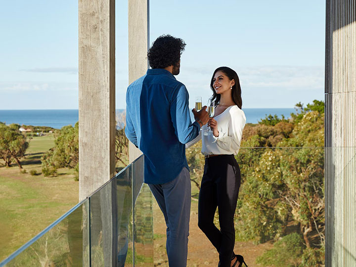 Couple having a drink on the balcony of their room at RACV Torquay Resort.