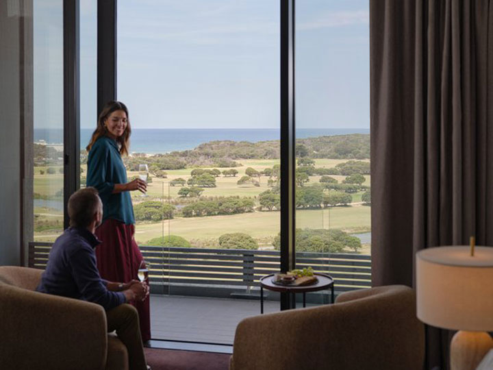 A couple enjoying a glass of wine with the view from a premium mountain room at RACV Healesville. 