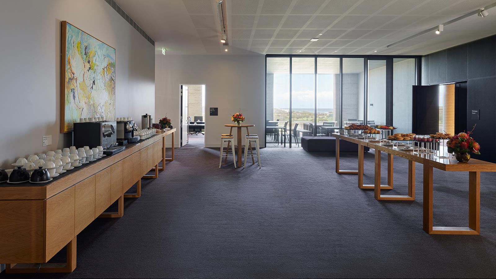 Tables lined with food in RACV Torquay Resort's Zeally 1 room, including a tea and coffee station, donuts and canapes.